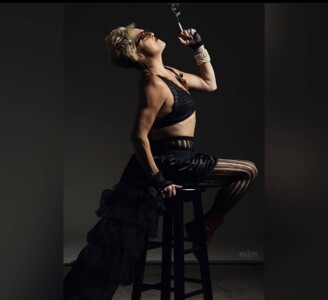 woman posing on chair in all black holding a cigarette